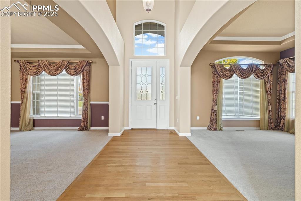 Image 2 of 33: Foyer entrance featuring light colored carpet, arched walkways, crown moldi