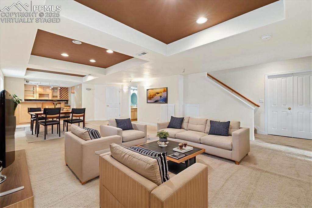 Image 21 of 33: Living area featuring a raised ceiling, recessed lighting, light carpet, an