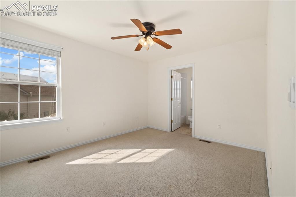 Image 22 of 33: Unfurnished bedroom featuring light carpet, a ceiling fan, and connected ba