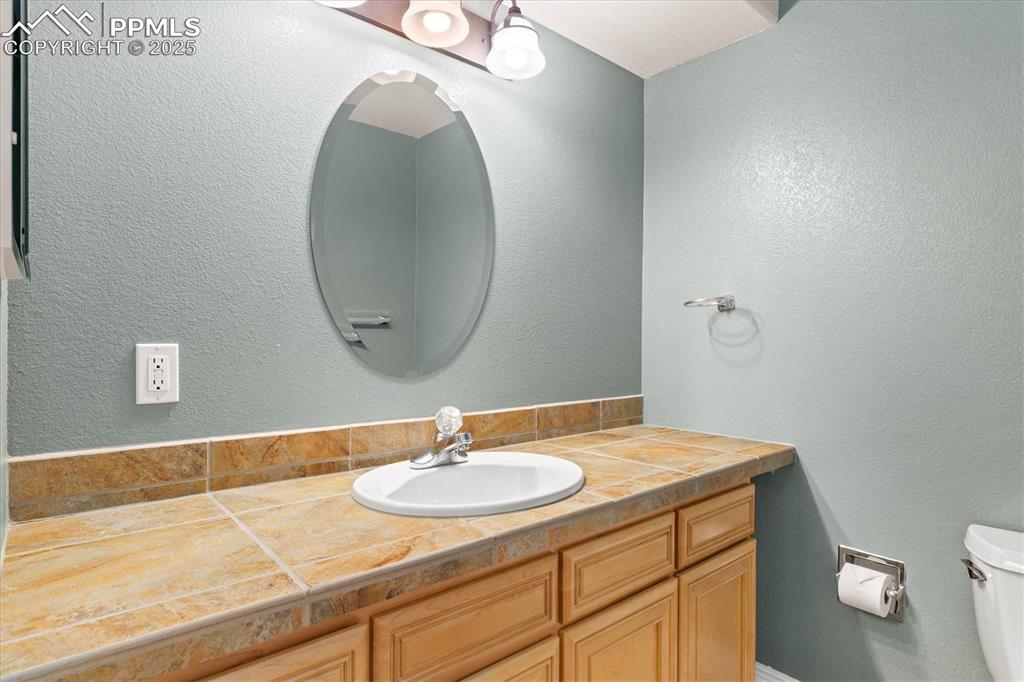 Image 26 of 33: Bathroom with a textured wall and vanity