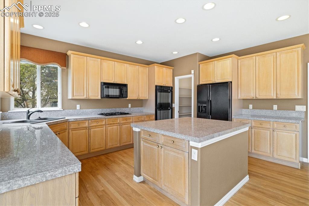 Image 7 of 33: Kitchen featuring light brown cabinets, recessed lighting, black appliances