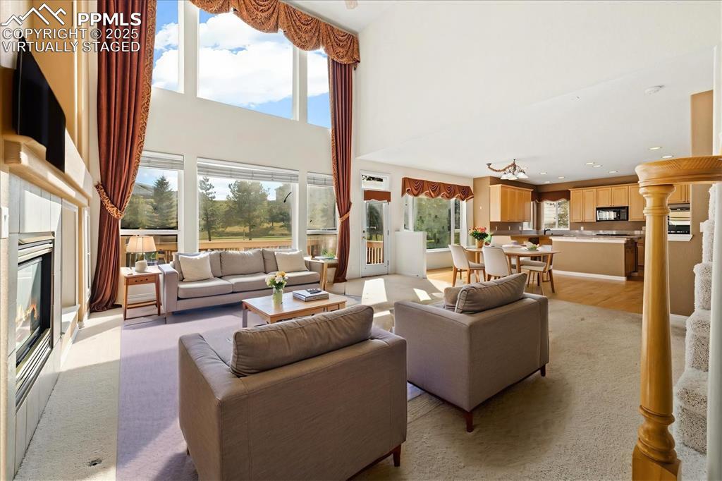 Image 8 of 33: Living room featuring a glass covered fireplace, 
light carpet, a high 
c