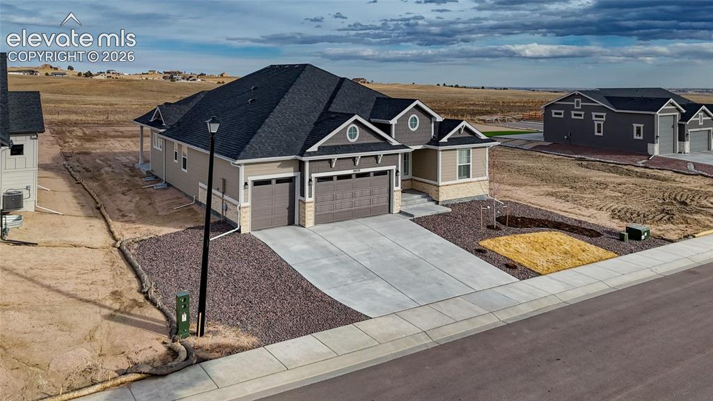 Image 1 of 50: View of front of property featuring a garage, concrete driveway, stone sidi