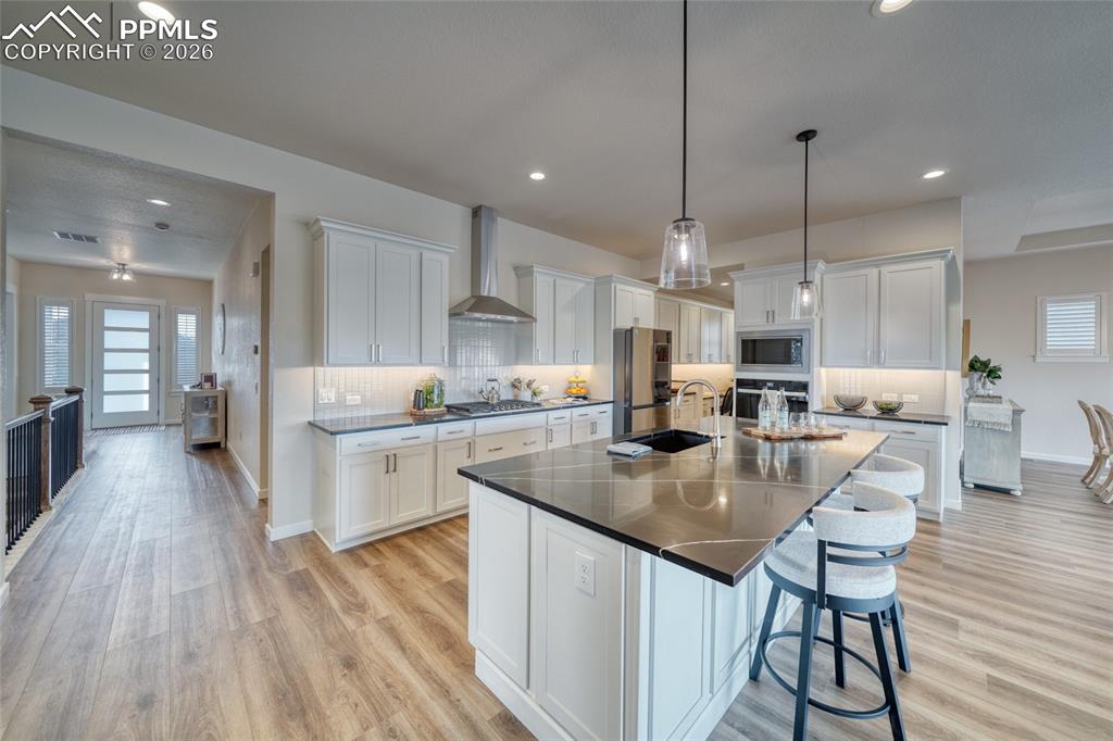 Image 14 of 50: Kitchen featuring white cabinetry, a breakfast bar, decorative backsplash, 