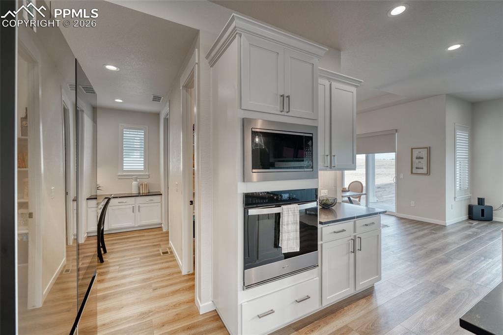 Image 16 of 50: Kitchen featuring white cabinetry, stainless steel appliances, light wood-t