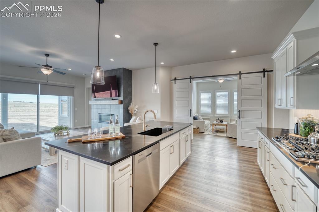 Image 17 of 50: Kitchen featuring a barn door, open floor plan, a ceiling fan, and a tile f