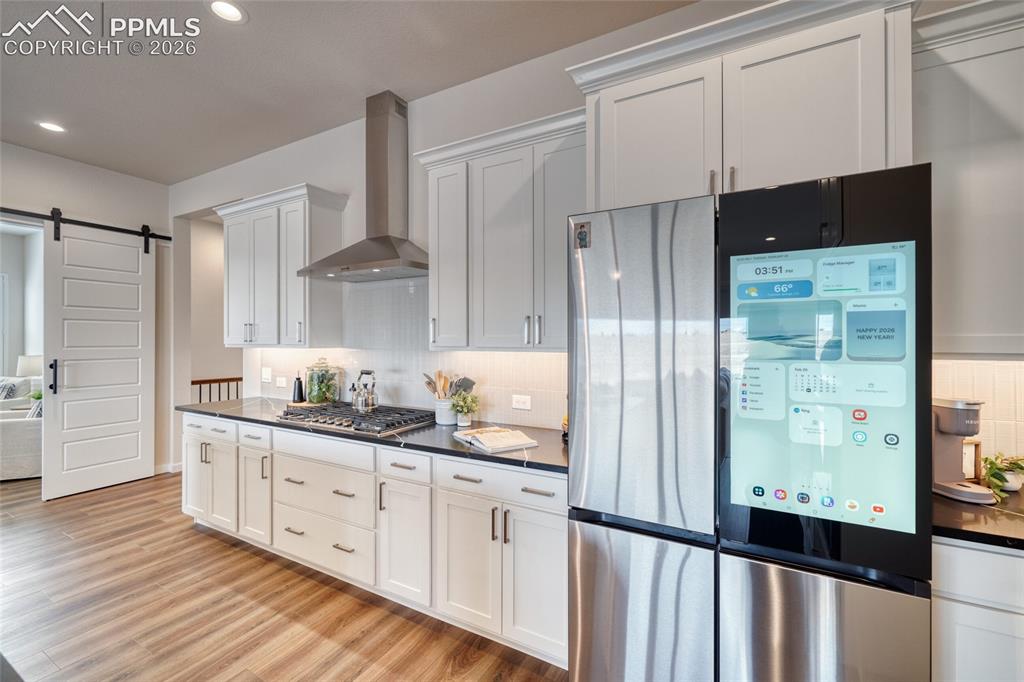 Image 18 of 50: Kitchen featuring stainless steel appliances, a barn door, white cabinets,