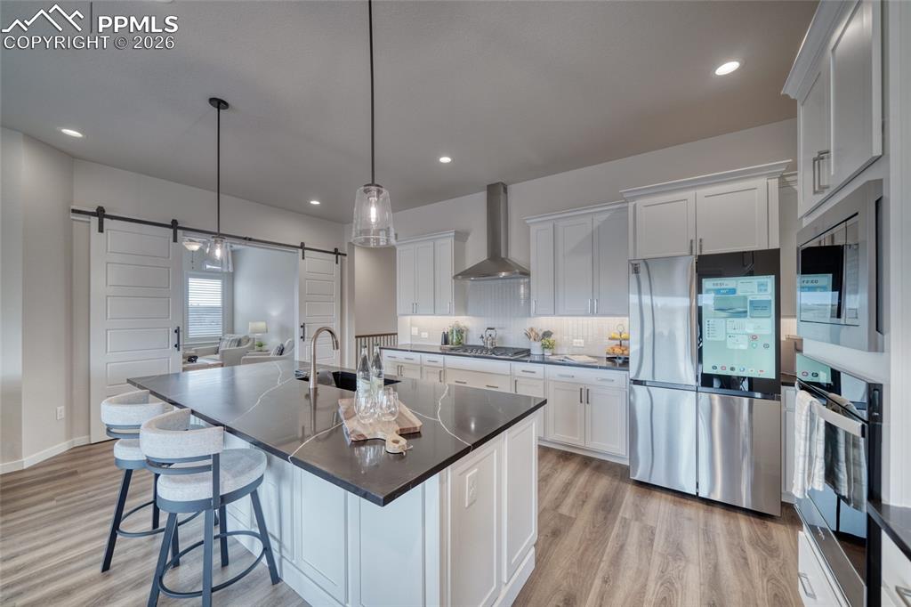 Image 19 of 50: Kitchen with stainless steel appliances, a breakfast bar area, white cabine