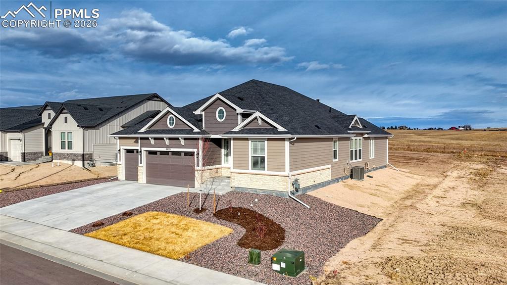 Image 2 of 50: Craftsman inspired home featuring stone siding, driveway, and an attached g
