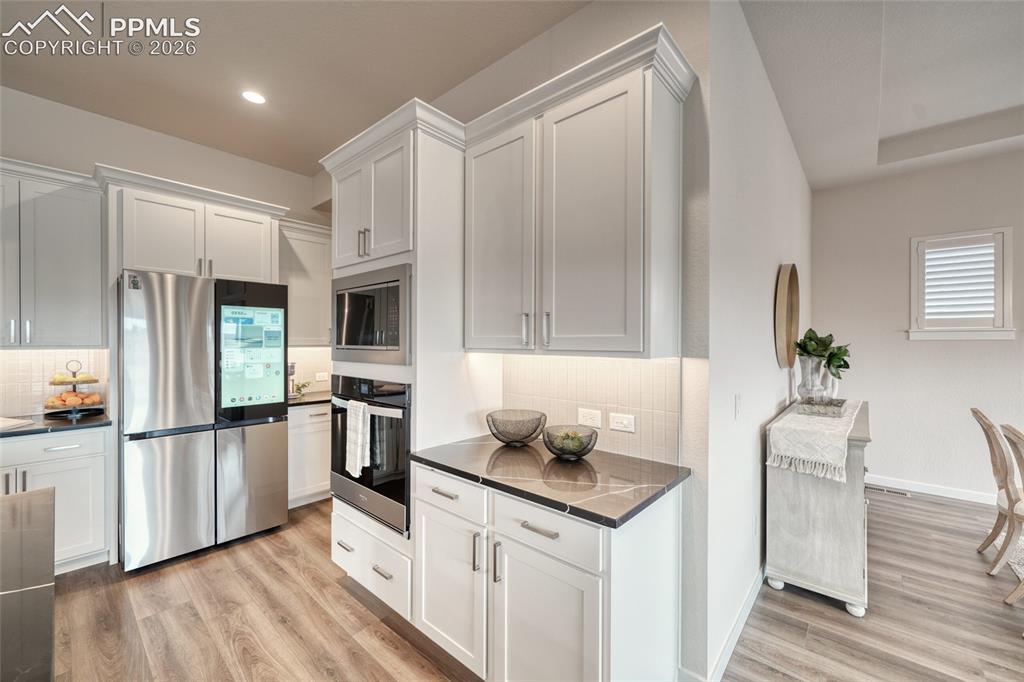 Image 20 of 50: Kitchen with stainless steel appliances, light wood-style flooring, decorat
