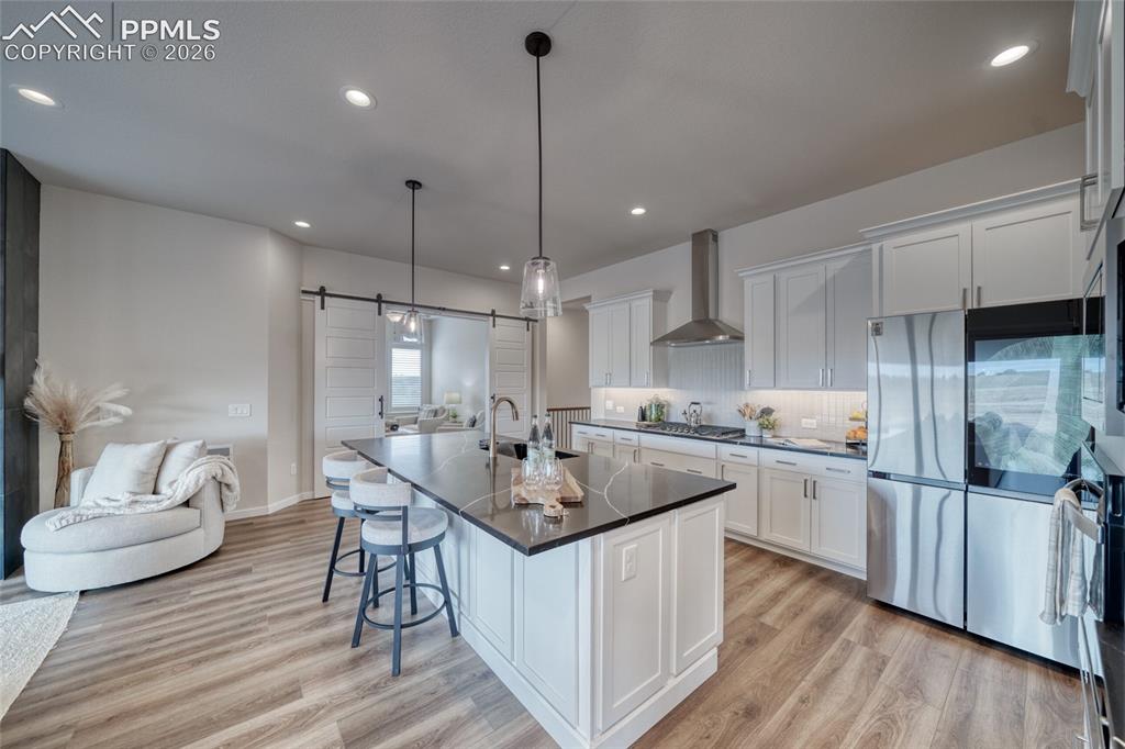 Image 21 of 50: Kitchen featuring a barn door, stainless steel appliances, a breakfast bar,