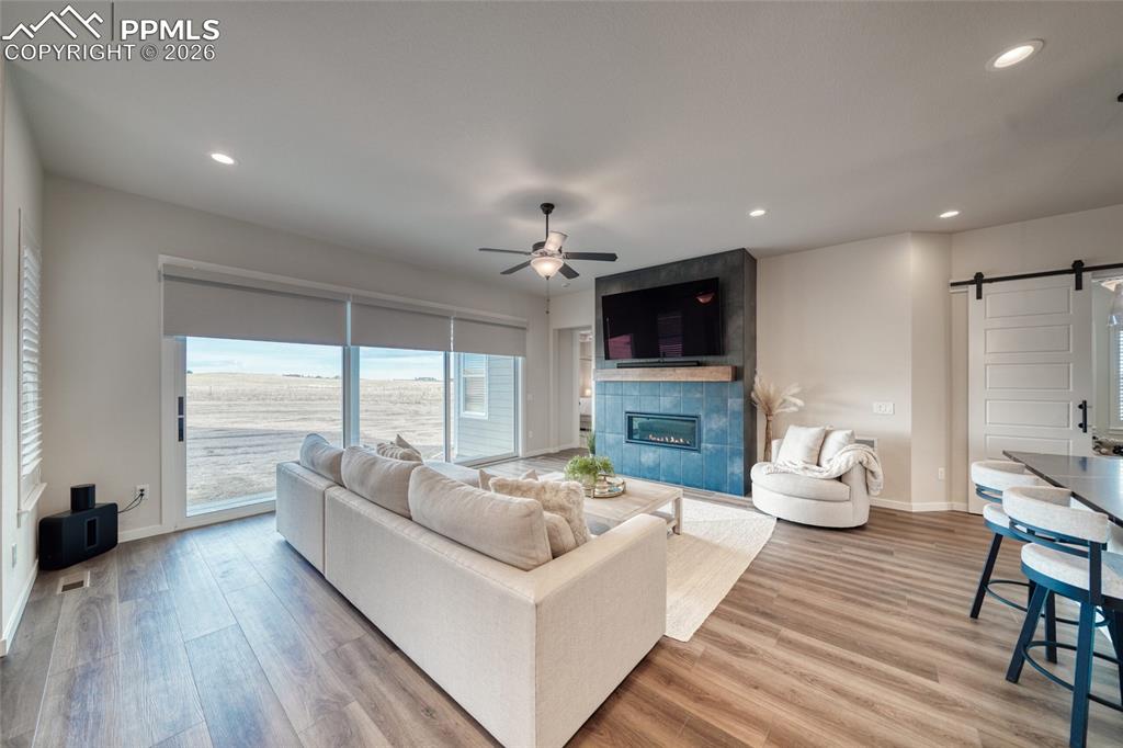 Image 22 of 50: Living area featuring a barn door, light wood-style flooring, a ceiling fan