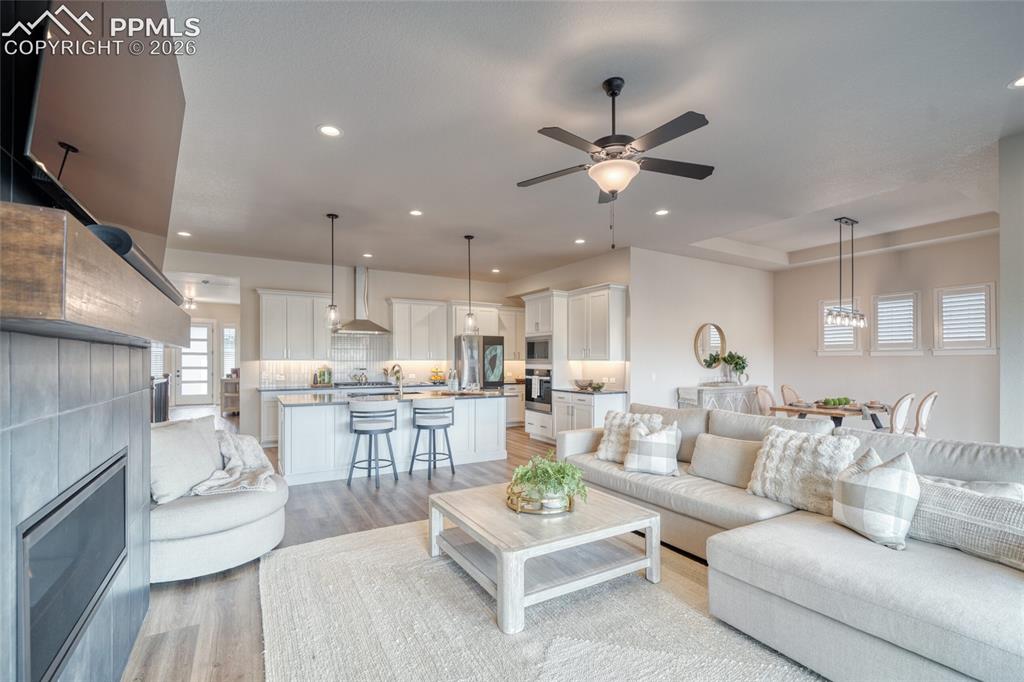 Image 24 of 50: Living area featuring light wood-style floors, a tiled fireplace, a ceiling