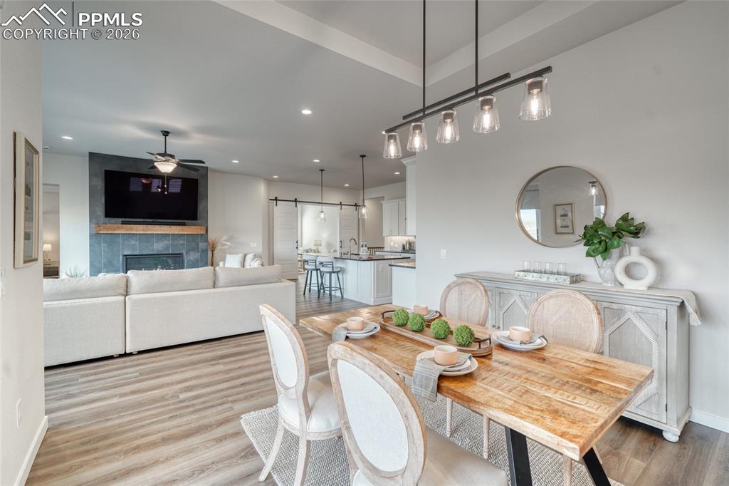 Image 26 of 50: Dining space featuring a barn door, light wood-type flooring, a tiled firep