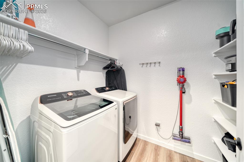Image 29 of 50: Laundry room featuring a textured wall, light wood-style floors, and washer