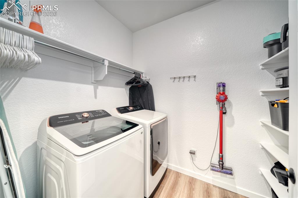 Image 29 of 50: Laundry room featuring a textured wall, light wood-style floors, and washer