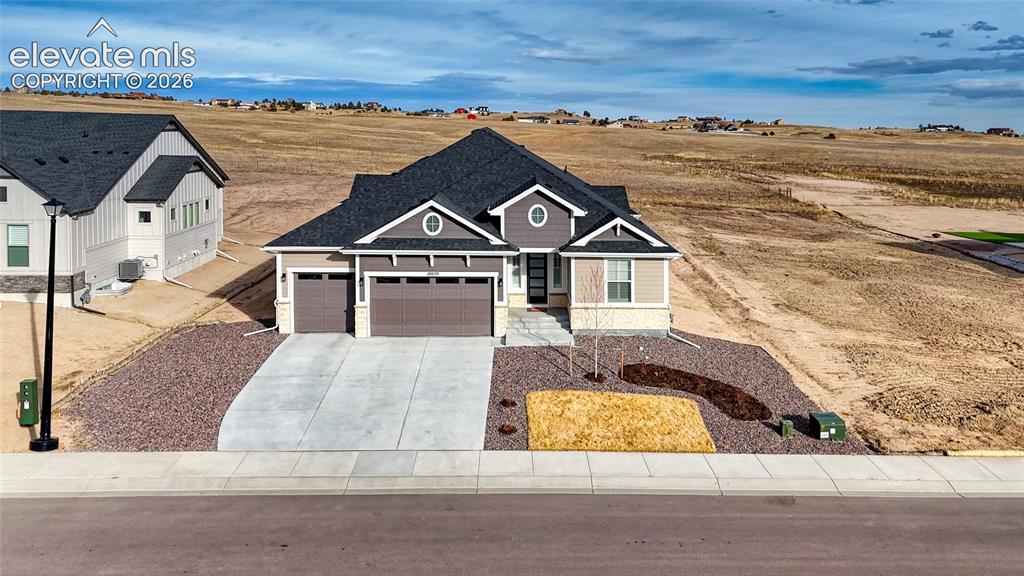 Image 3 of 50: View of front of home with an attached garage, concrete driveway, and stone