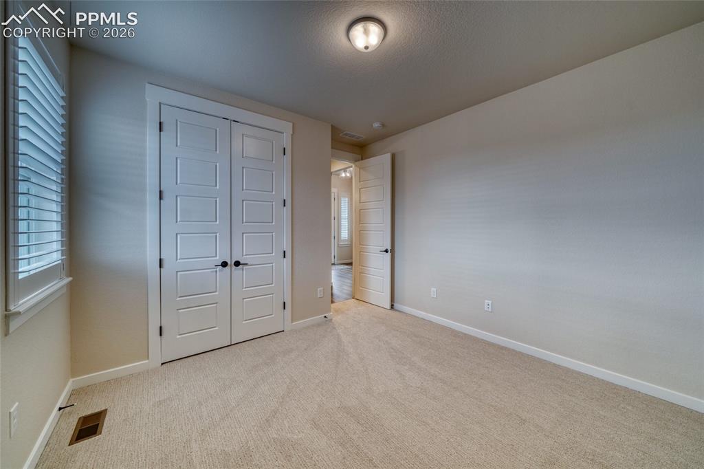 Image 43 of 50: Unfurnished bedroom featuring a closet, light colored carpet, and a texture