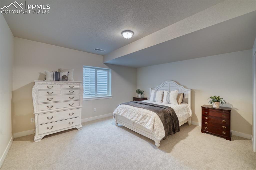 Image 47 of 50: Bedroom with light colored carpet and a textured ceiling