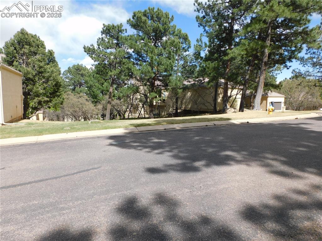 Image 7 of 9: Residential street with paved road, concrete sidewalk, and manicured green 