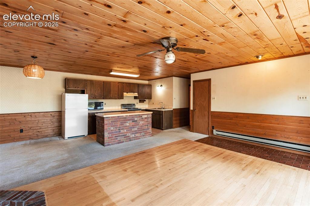 Image 11 of 46: Open-concept space featuring a wood-panel ceiling, a functional kitchenette