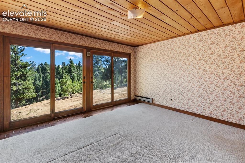 Image 18 of 46: Room featuring a wood-panel ceiling, patterned wallpaper, and light-toned c