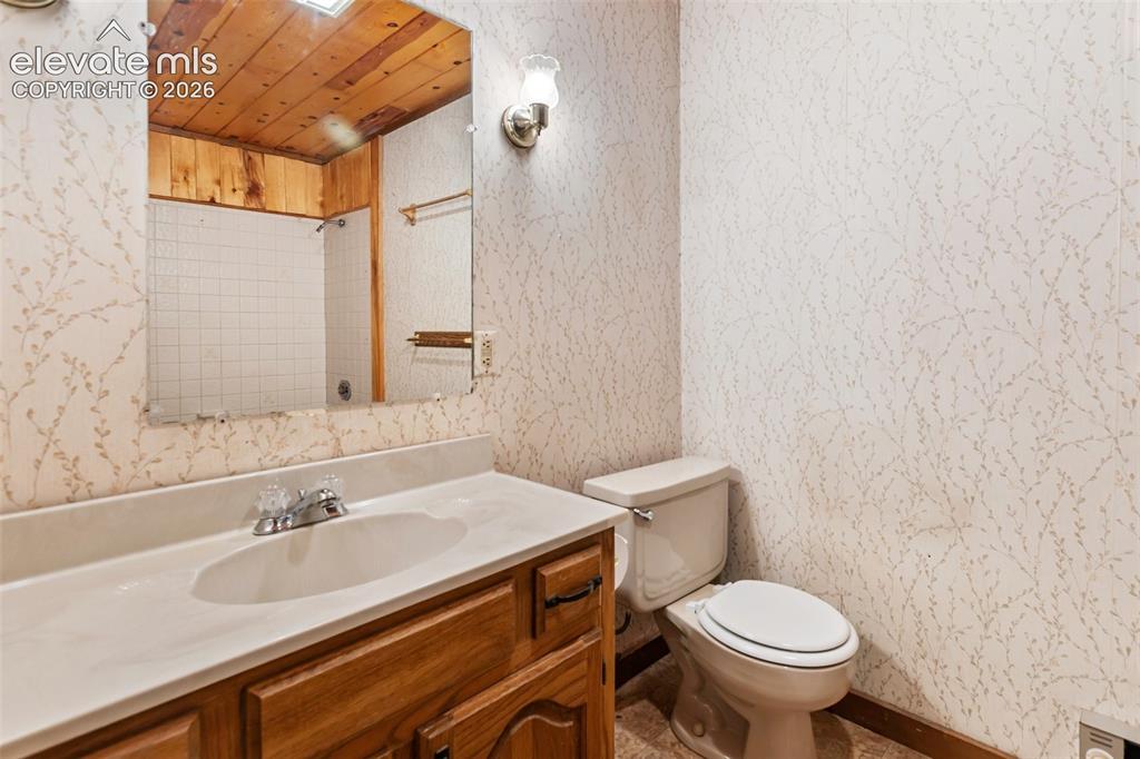 Image 24 of 46: Bathroom featuring a wood-panel ceiling, vanity with a built-in sink, and w