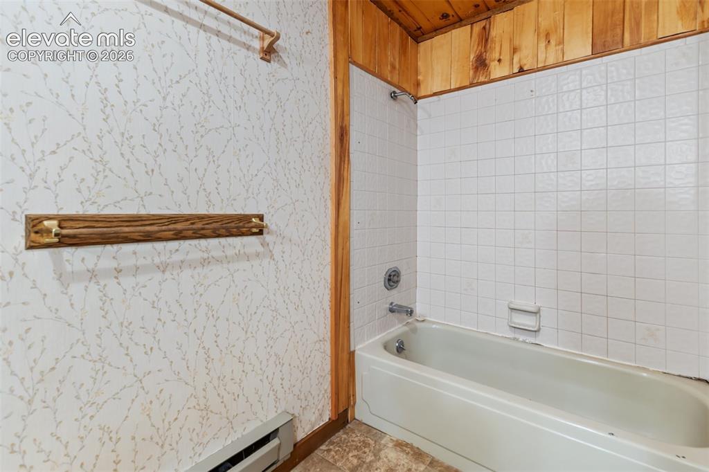 Image 25 of 46: Bathtub with white square tile surround and chrome fixtures