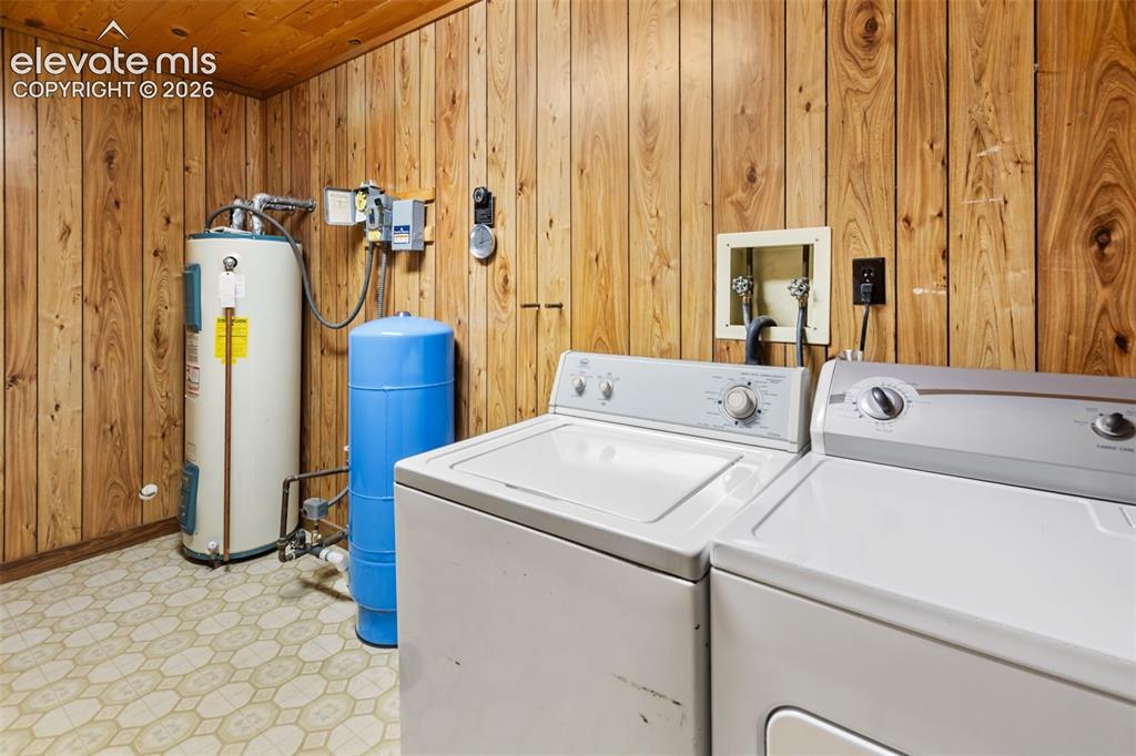 Image 27 of 46: Utility area with wood-paneled walls and ceiling, patterned vinyl flooring,