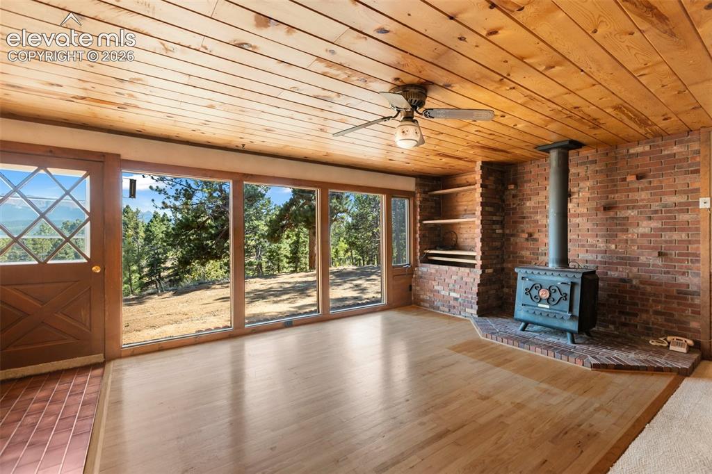 Image 3 of 46: Wood-paneled ceiling with an overhead fan, brick wall with built-in shelvin