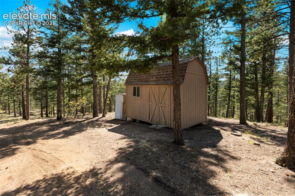Image 33 of 46: Wood-sided shed with a gambrel roof and double barn doors