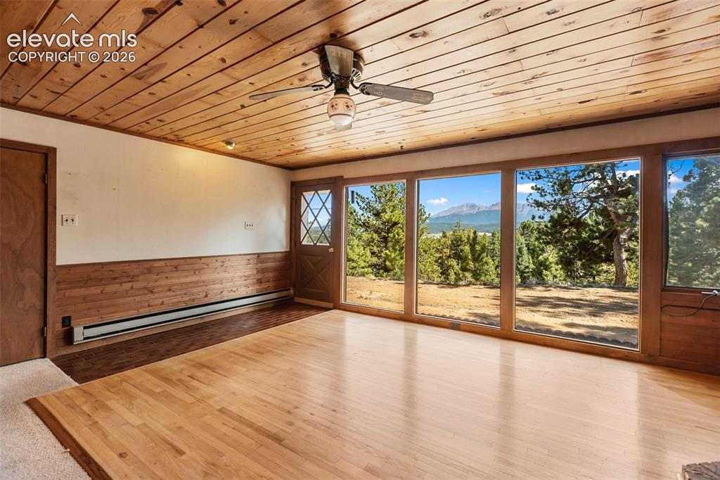 Image 8 of 46: Expansive window wall with mountain backdrop, wood paneling, wood-finish fl
