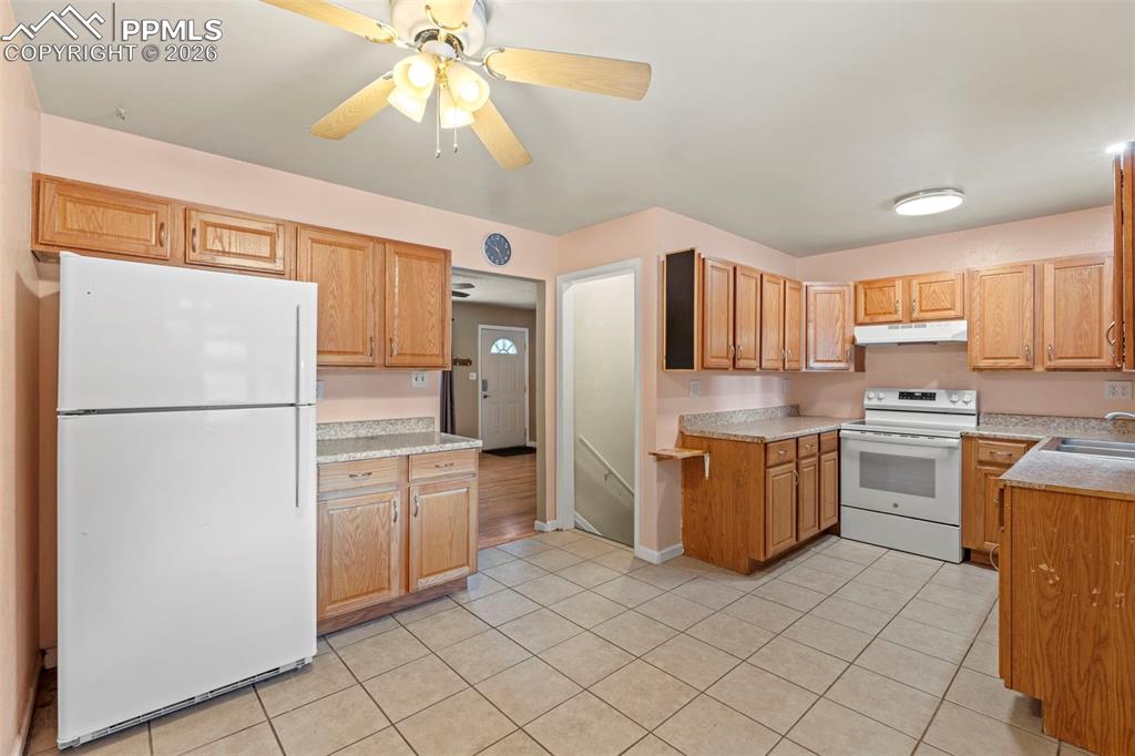 Image 11 of 28: Kitchen featuring white appliances, light countertops, a ceiling fan, under