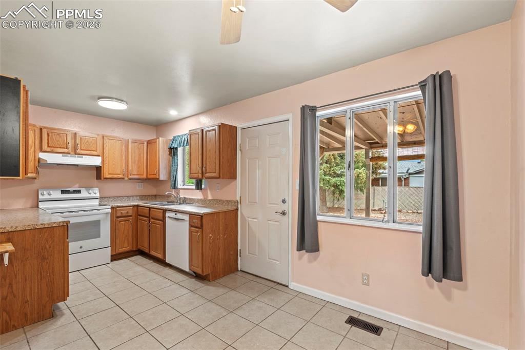 Image 12 of 28: Kitchen featuring white appliances, plenty of natural light, light tile pat