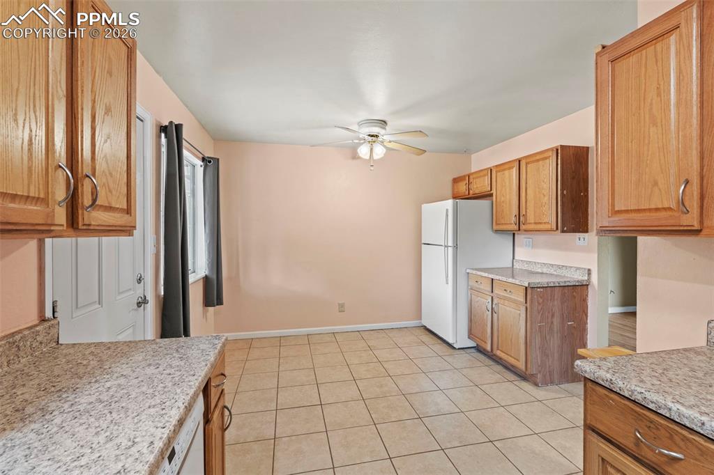 Image 16 of 28: Kitchen with freestanding refrigerator, a ceiling fan, light tile patterned