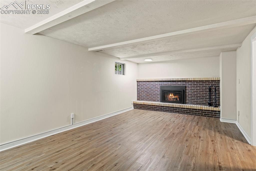 Image 19 of 28: Unfurnished living room with a textured ceiling, a fireplace, light wood-ty