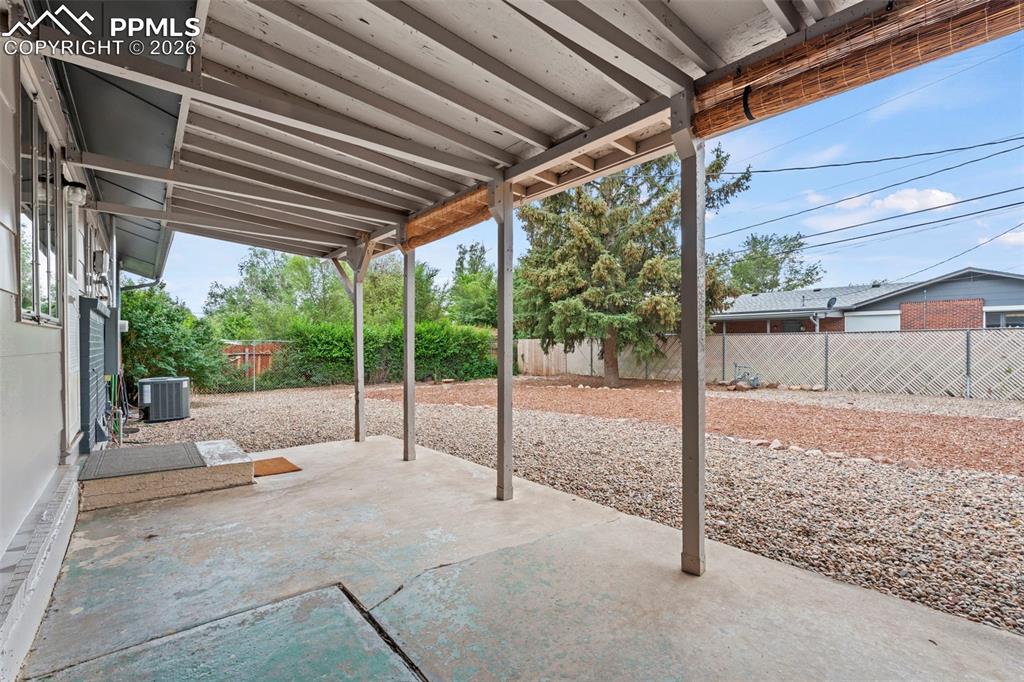 Image 27 of 28: Fenced backyard with a patio area