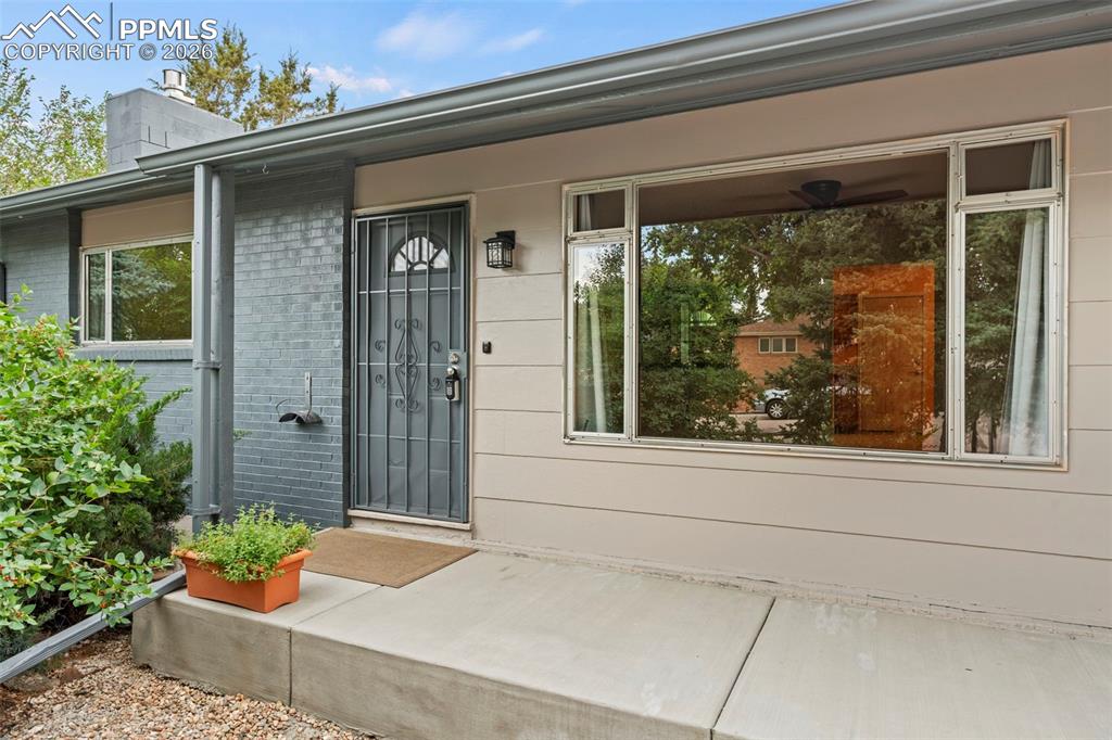 Image 4 of 28: View of exterior entry with brick siding, a chimney, and covered porch