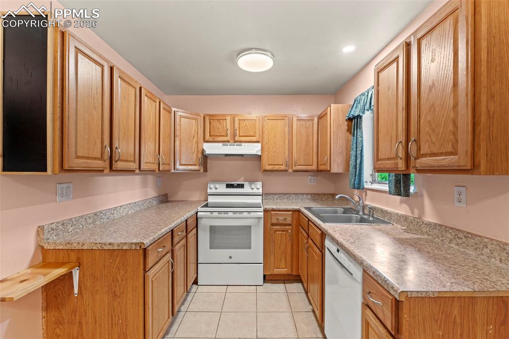 Image 9 of 28: Kitchen featuring white appliances, light countertops, under cabinet range 