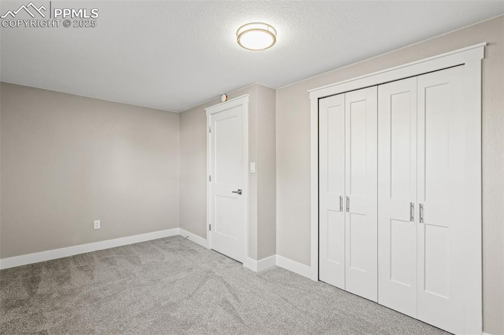 Image 11 of 15: Unfurnished bedroom with light carpet, a closet, and a textured ceiling
