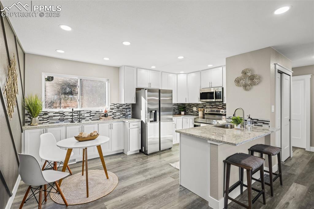 Image 5 of 15: Kitchen featuring appliances with stainless steel finishes, light stone cou