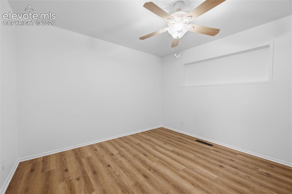 Image 20 of 38: Room featuring wood-finish flooring, white walls, and a ceiling fan with in