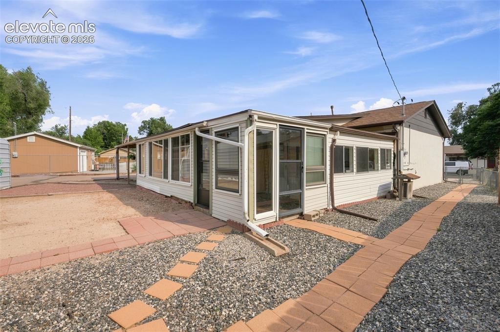 Image 33 of 38: Rear exterior featuring an enclosed sunroom with multiple windows, a covere
