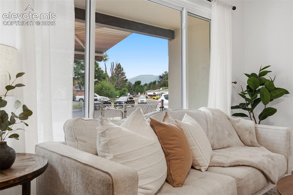 Image 8 of 38: Bright living area featuring wood-finish flooring, a ceiling fan with integ