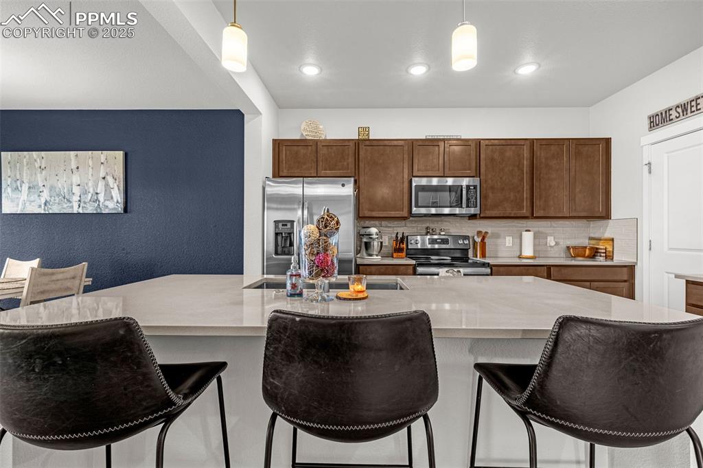 Image 4 of 33: Kitchen featuring tasteful backsplash, stainless steel appliances, hanging 