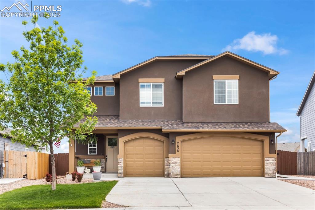 Caption: View of front facade featuring stone siding, driveway, a garage, and stucco siding