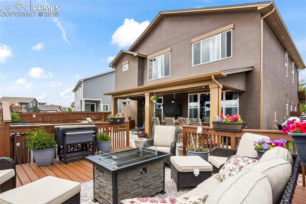 Image 14 of 45: Wooden deck with an outdoor living space with a fire pit and a pool.