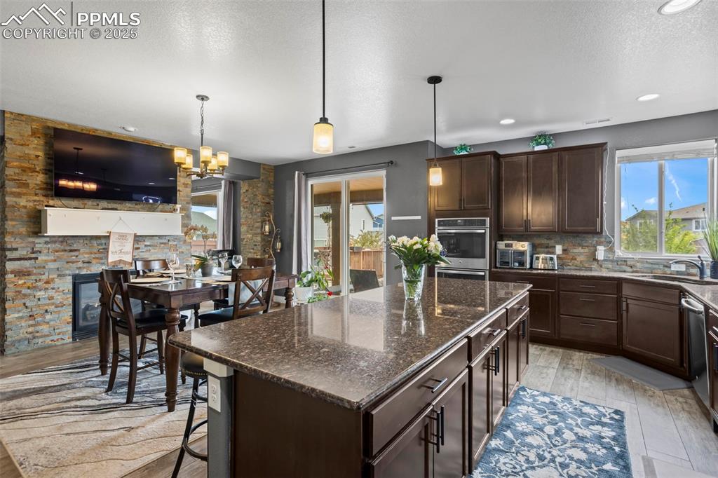 Image 24 of 45: Kitchen featuring dark brown cabinetry, a sink, a textured ceiling, a cente