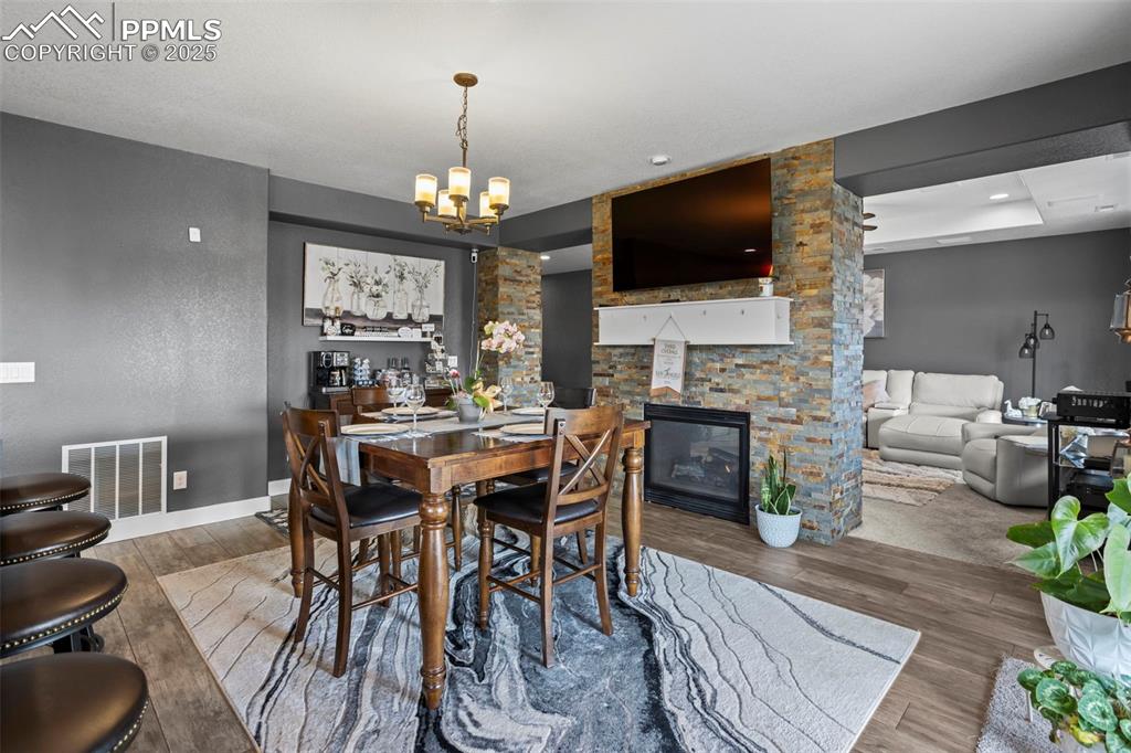Image 26 of 45: Dining space featuring a chandelier, wood finished floors, gas fireplace, a