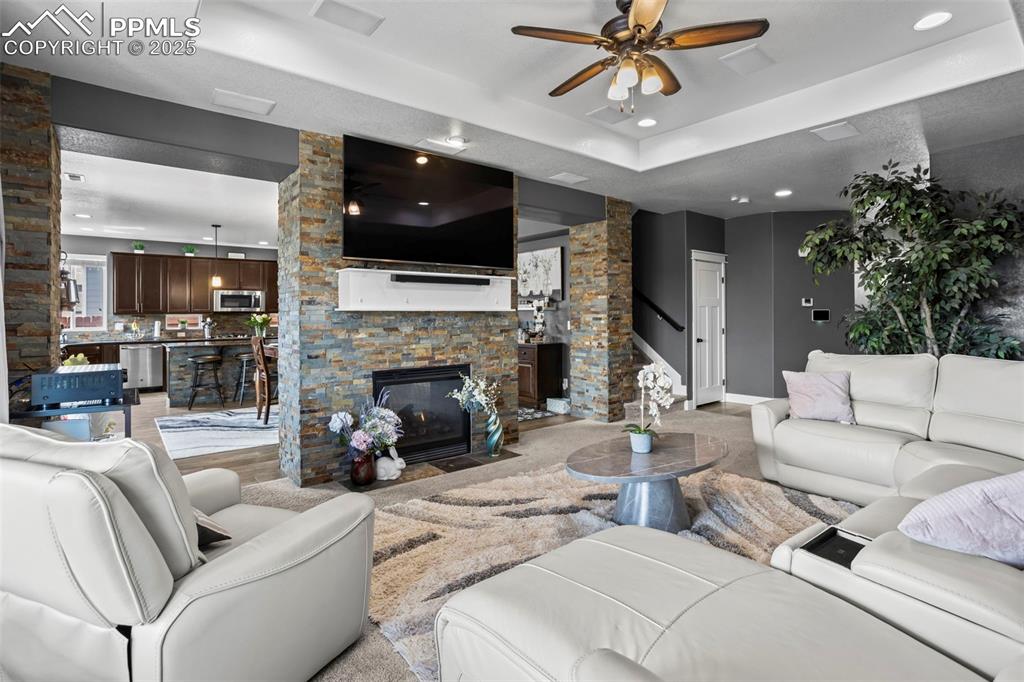 Image 29 of 45: Living area with a raised ceiling, a ceiling fan, recessed lighting, and a 